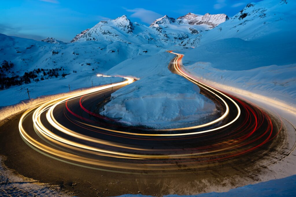 Lichter auf Strasse zu schneebedeckten Bergen.